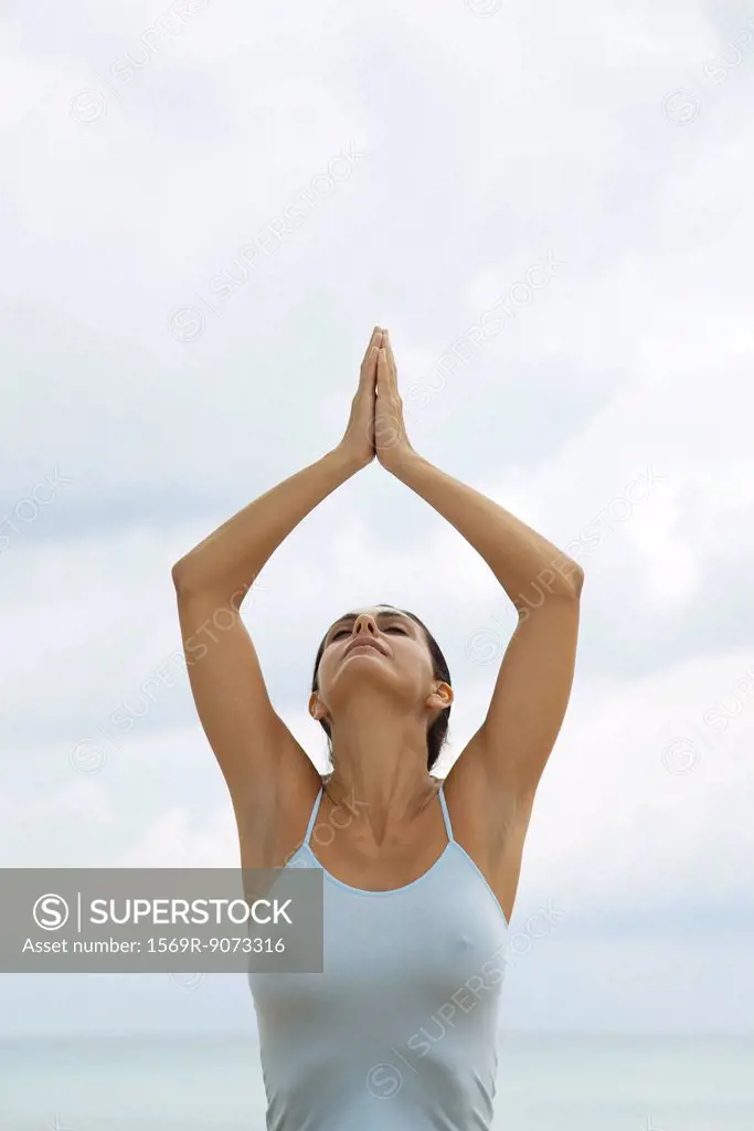 Mature woman in prayer position with arms above head