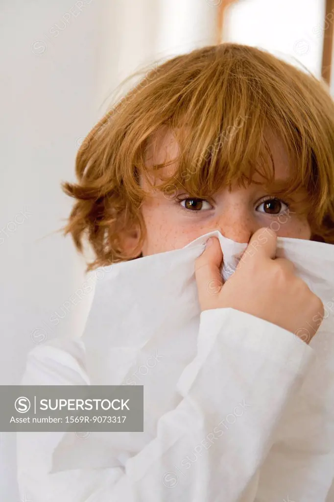 Boy blowing nose on tissue