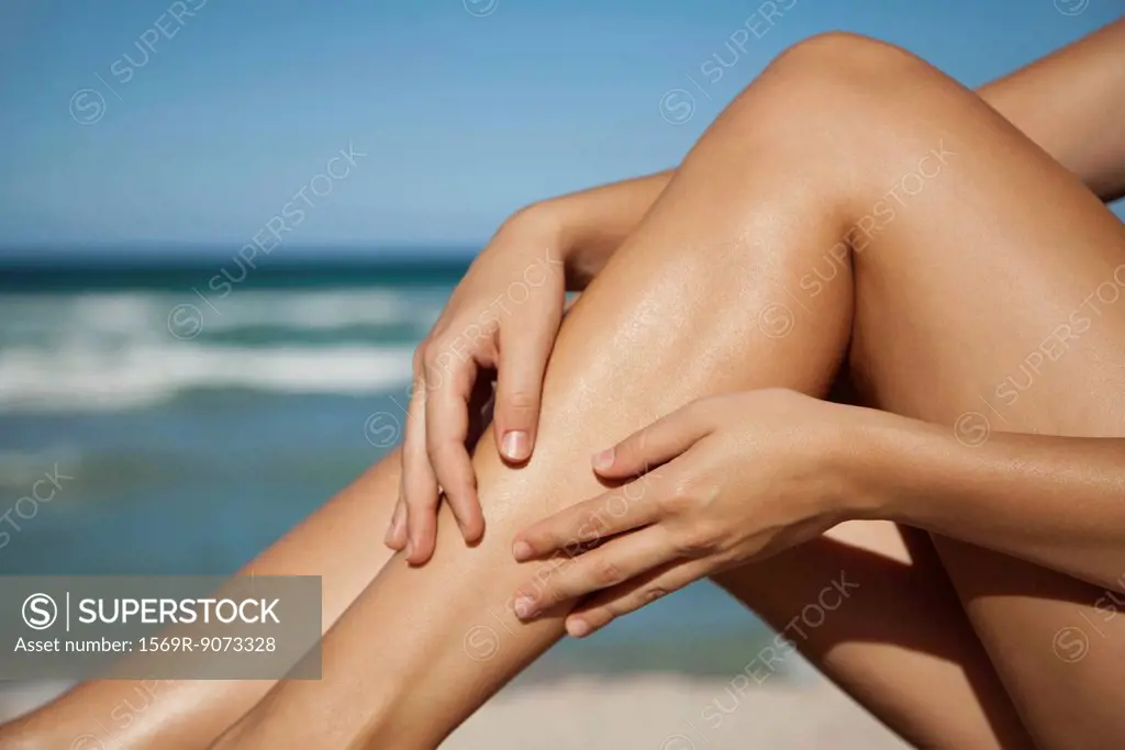Woman rubbing legs, low section