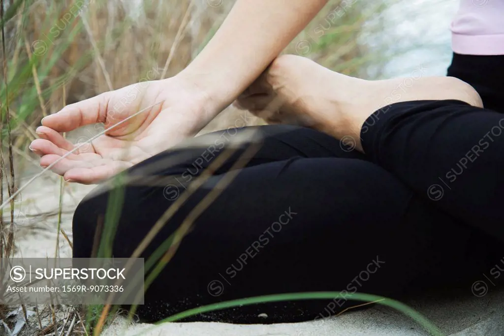 Woman sitting in lotus position, fingers in meditation position, cropped