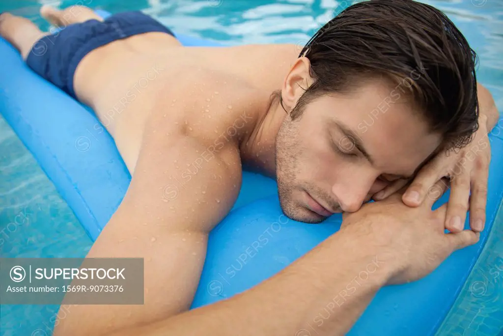 Young man lying on stomach on inflatable float