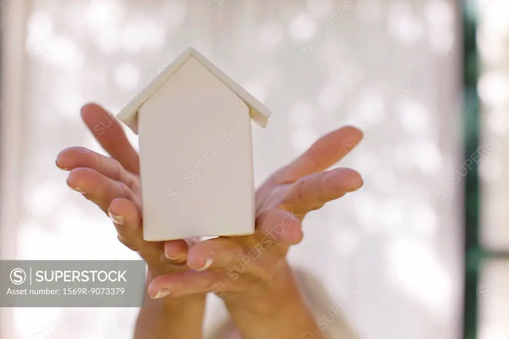 Woman´s hands holding small model house, cropped