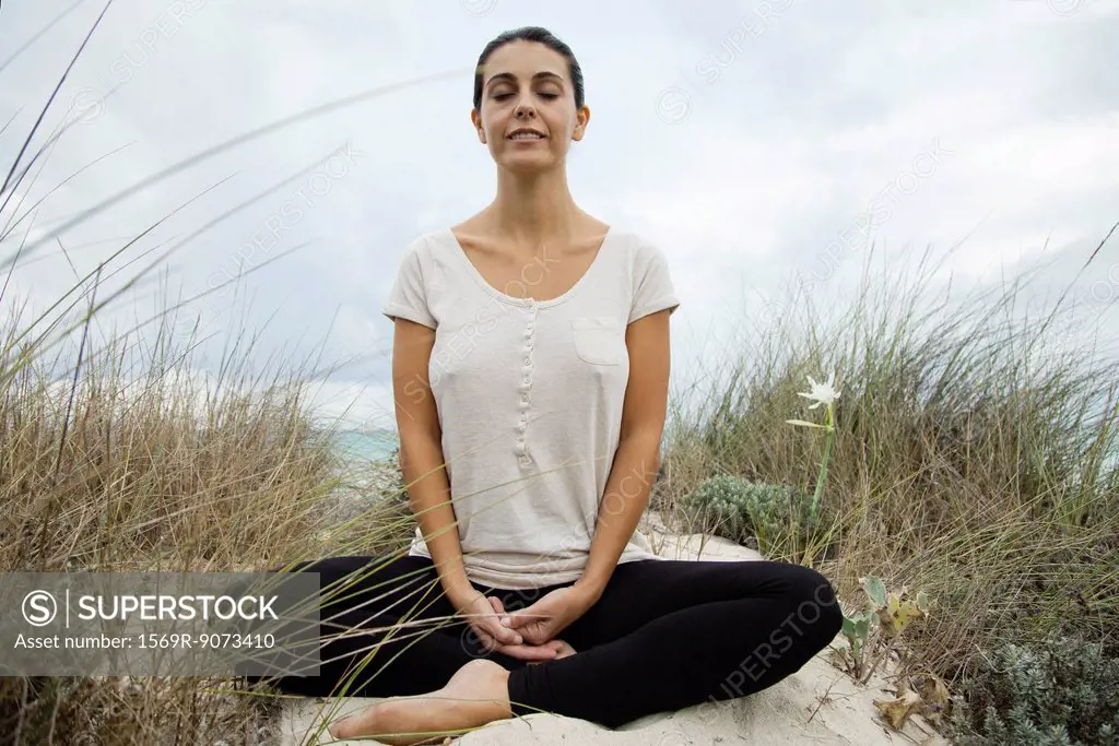 Smiling mature woman meditating on beach, portrait