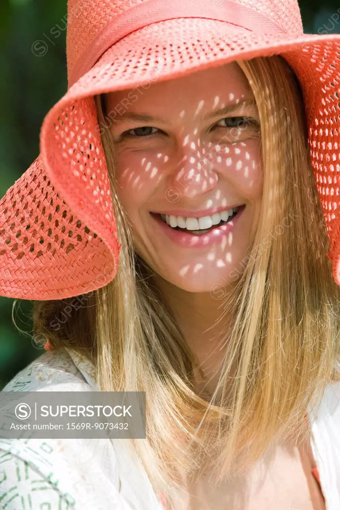 Smiling young woman with straw hat, portrait