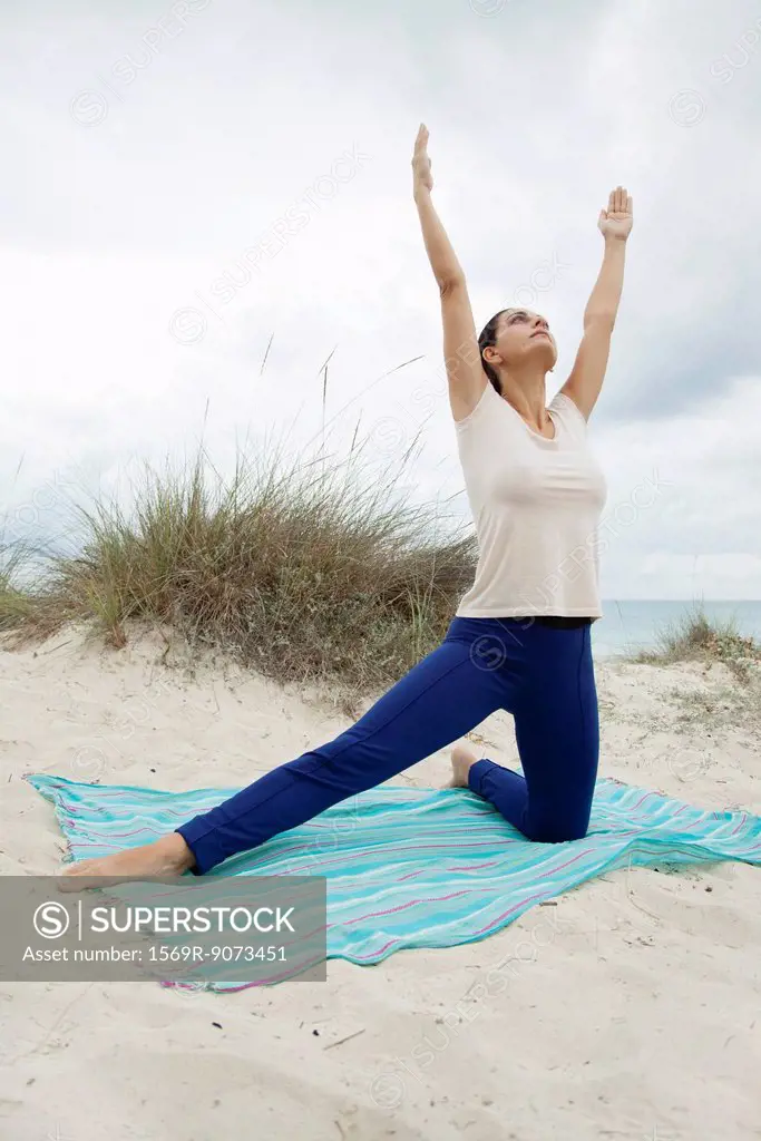 Mature woman practicing yoga on beach