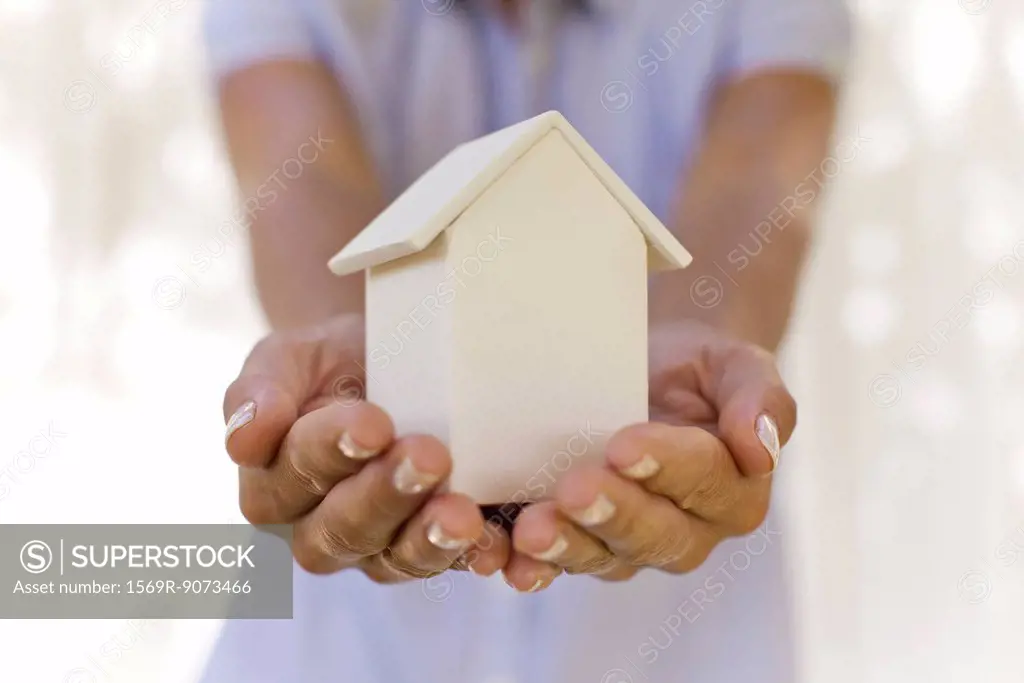 Woman holding small model house, cropped