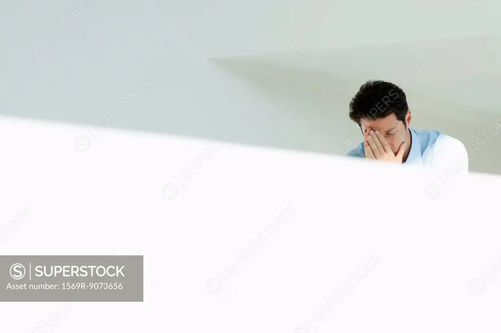 Distressed man covering face with hands