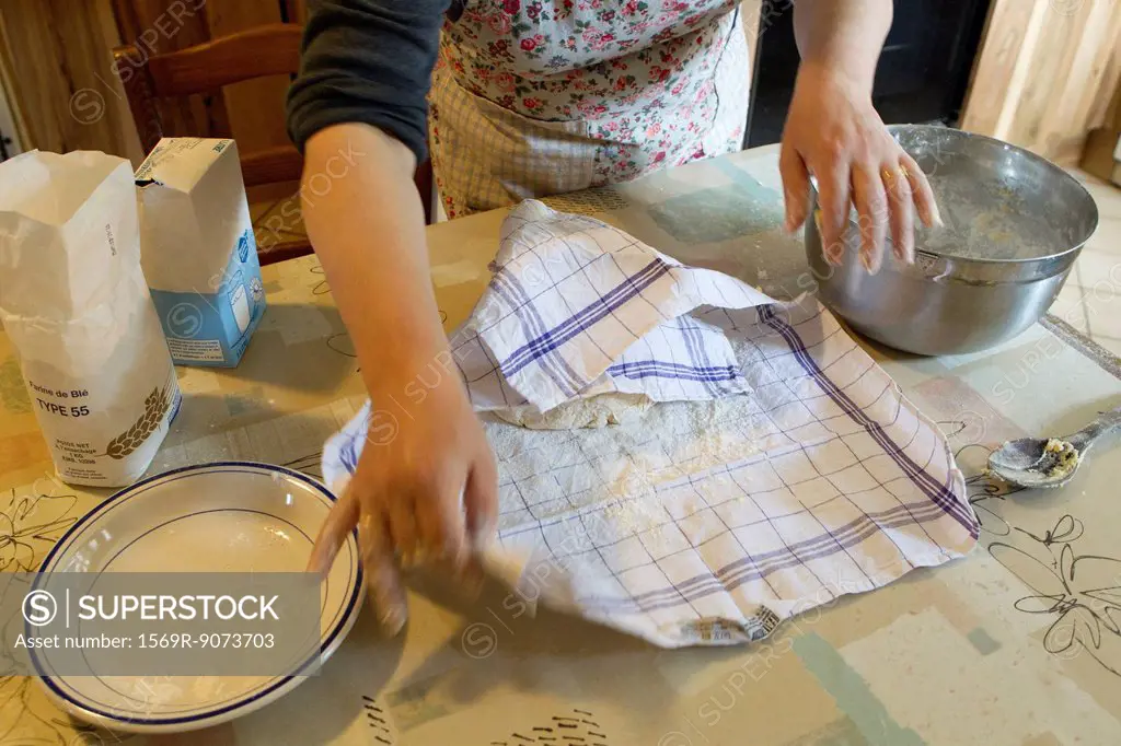 Woman covering pastry dough with towel, cropped