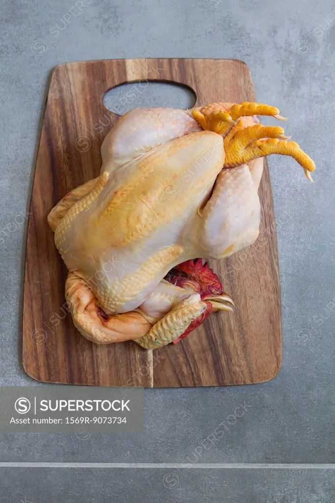 Whole raw chicken on cutting board