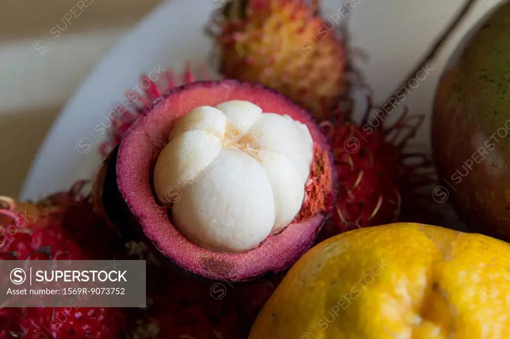 Halved mangosteen and other tropical fruits