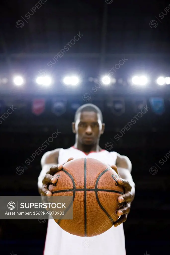 Basketball player holding basketball, focus on foreground