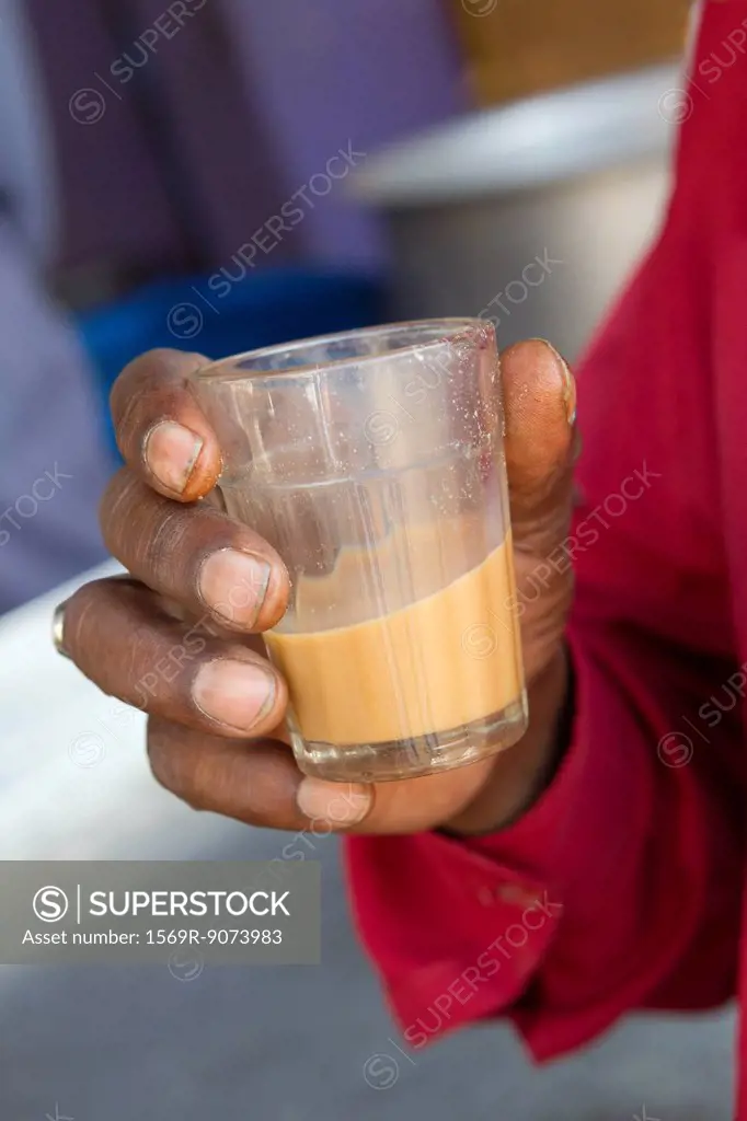 Man holding glass of chai tea, cropped