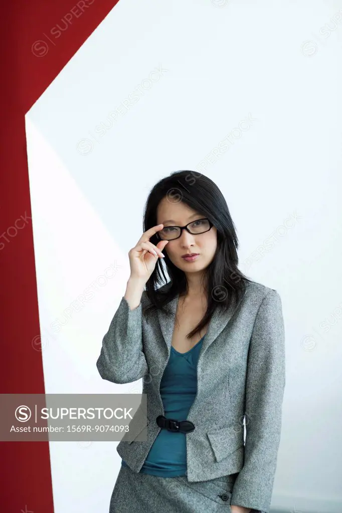 Businesswoman adjusting glasses, portrait