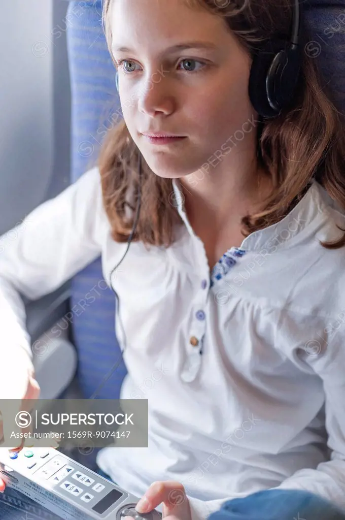 Girl using remote control to change channels on airplane