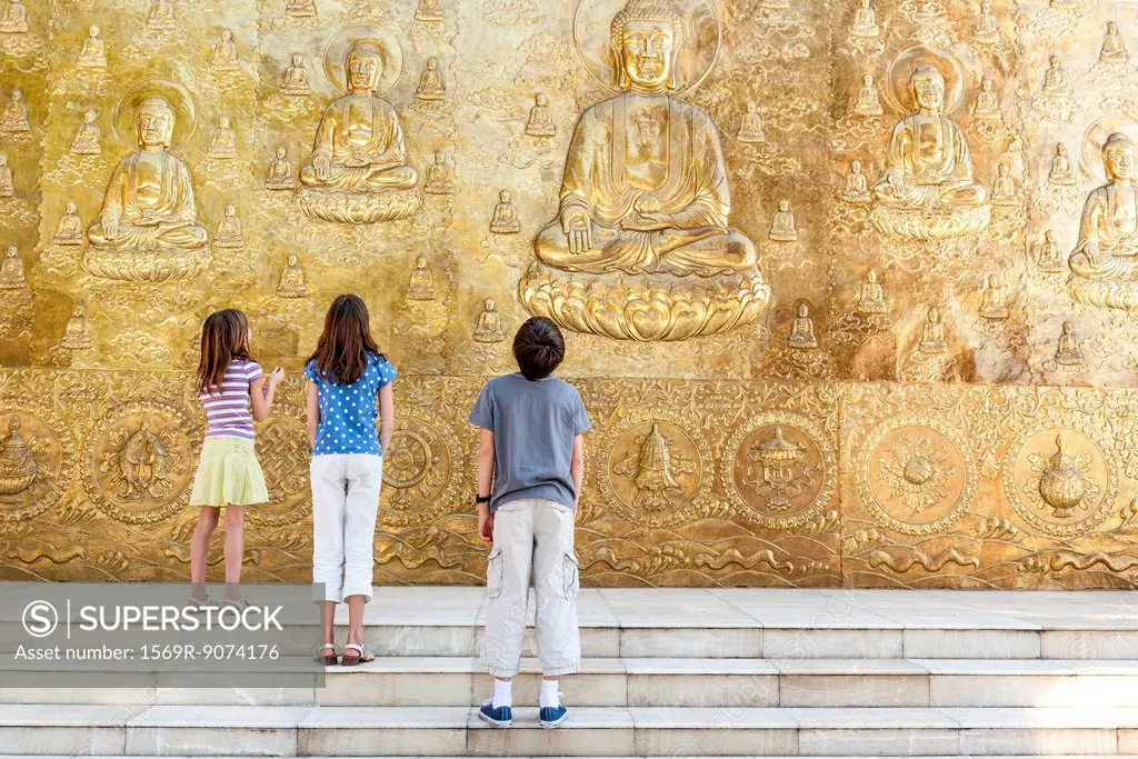 Young tourists looking up at Buddhist bas_relief