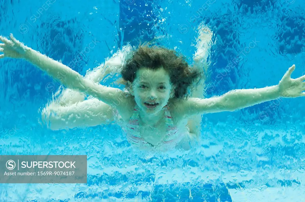 Girl swimming underwater in swimming pool