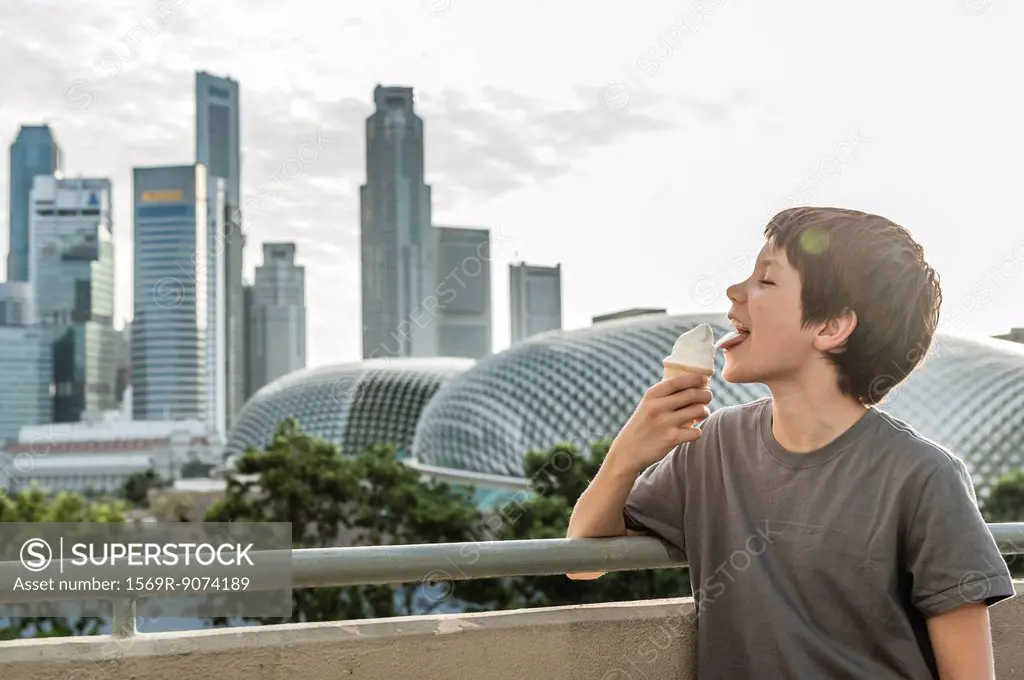 Boy eating ice cream cone, city skyline in background