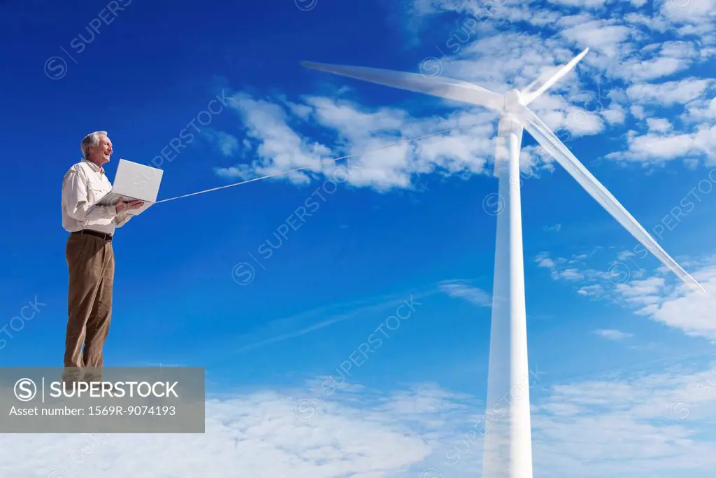 Man standing on cloud, using laptop computer powered by wind turbine