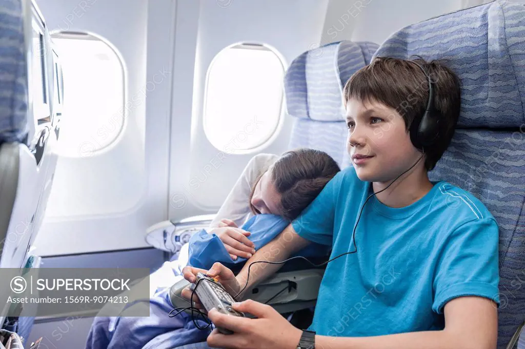 Boy using remote control to change channels on airplane