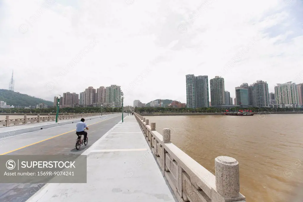 Man riding bicycle on bridge, Shandong province, China