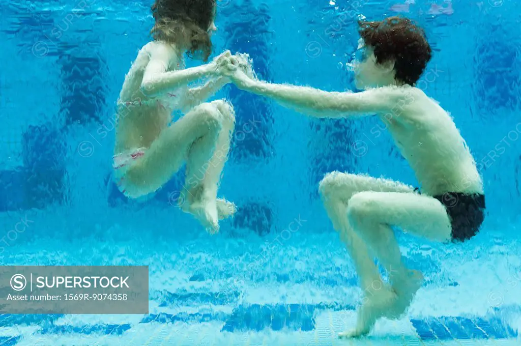 Brother and sister playing underwater in swimming pool