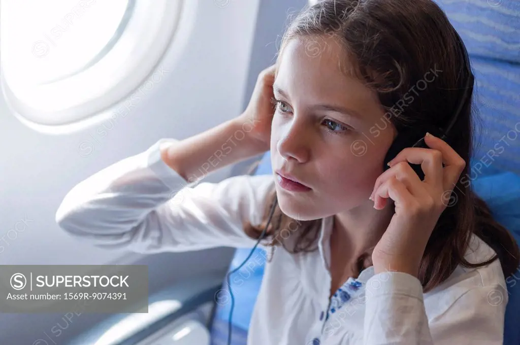Girl listening to music on airplane with headphones