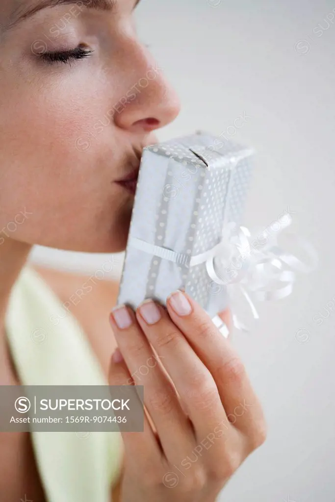 Woman kissing wrapped gift, eyes closed