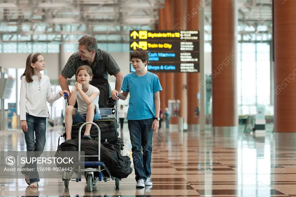 Family pushing luggage cart in airport