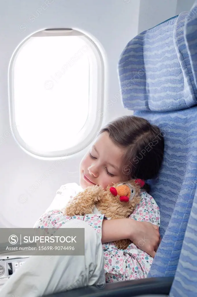 Girl embracing stuffed toy on airplane