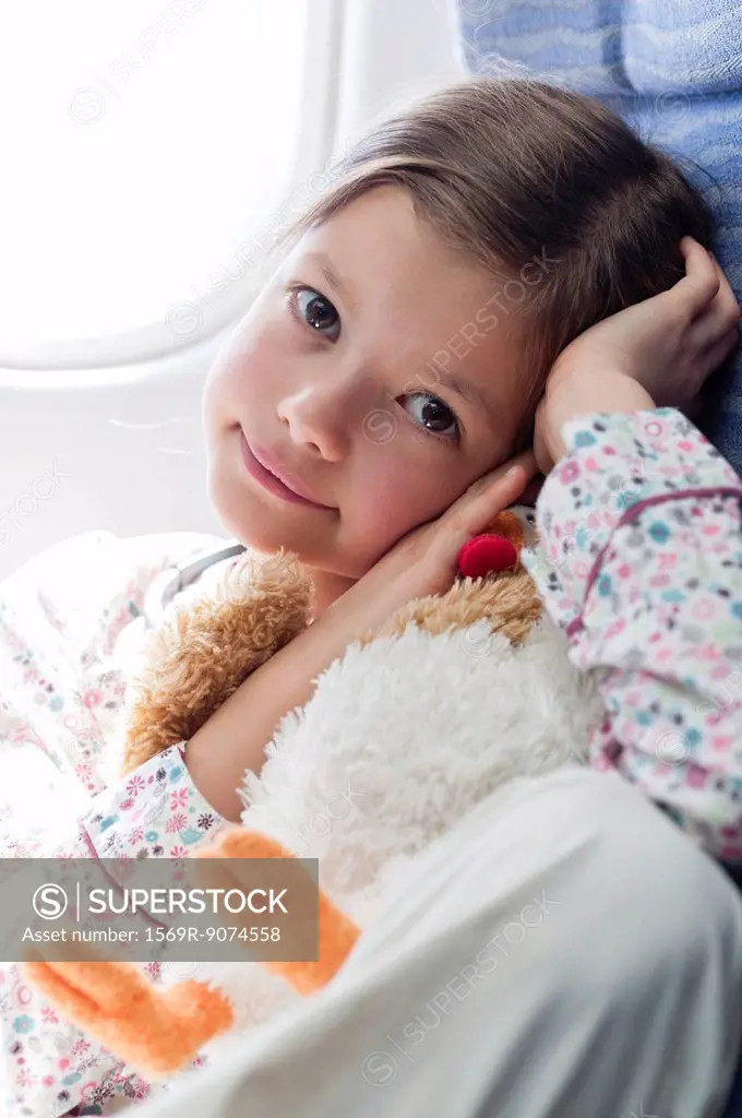 Girl holding stuffed toy on airplane, portrait