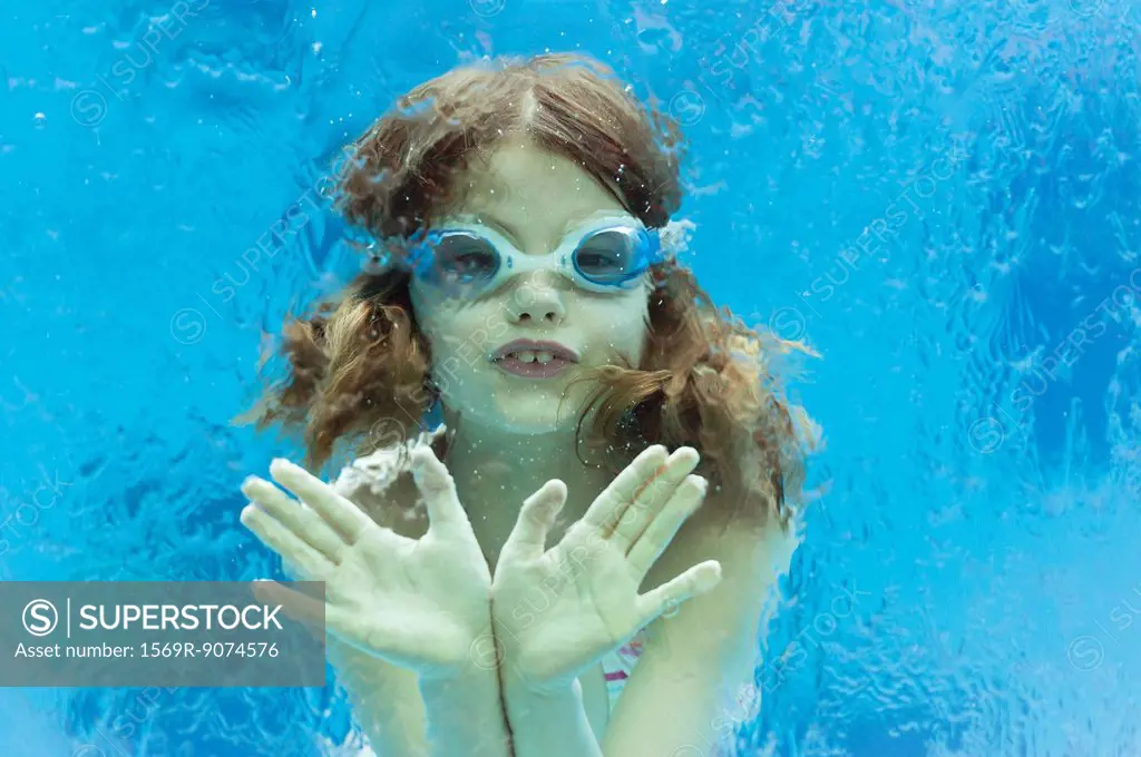 Girl wearing goggles swimming underwater in swimming pool