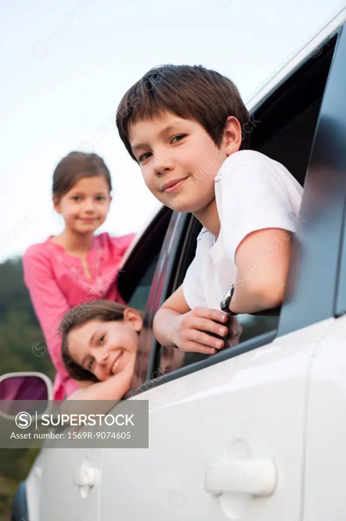 Siblings leaning out of car window, smiling, portrait