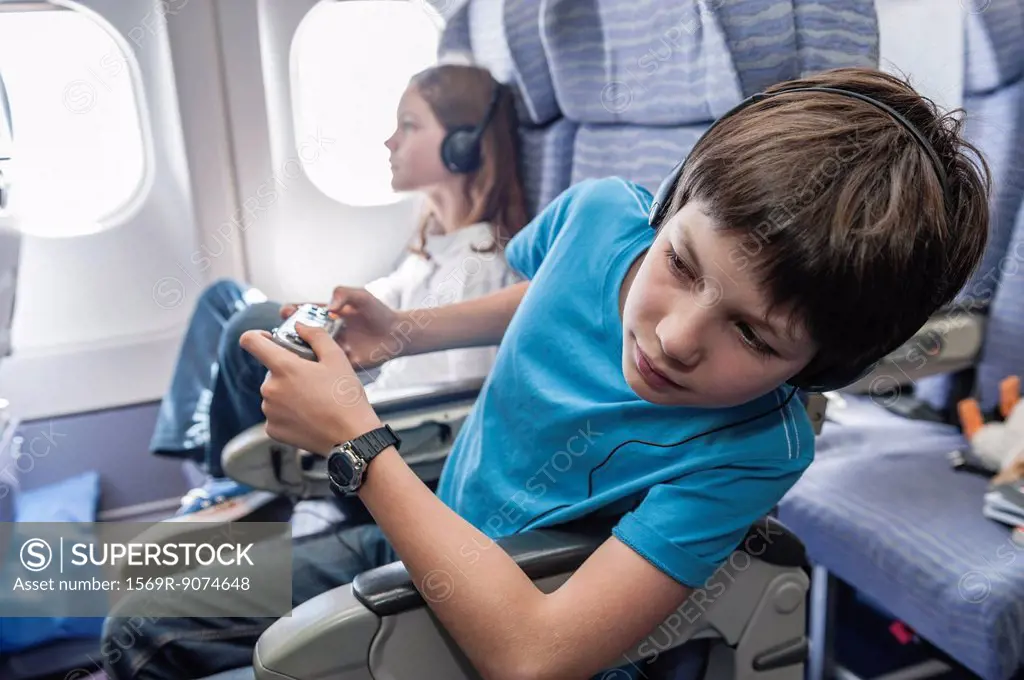 Boy leaning out of seat on airplane to look down aisle