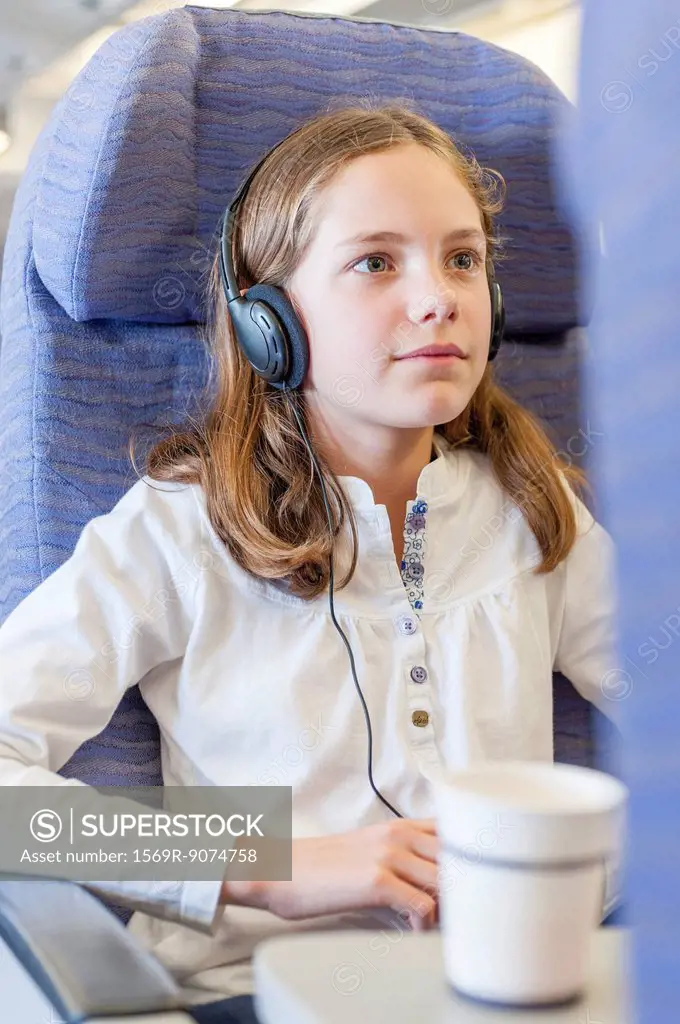 Girl watching movie with headphones on airplane