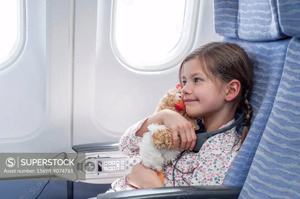 Girl embracing stuffed toy on airplane