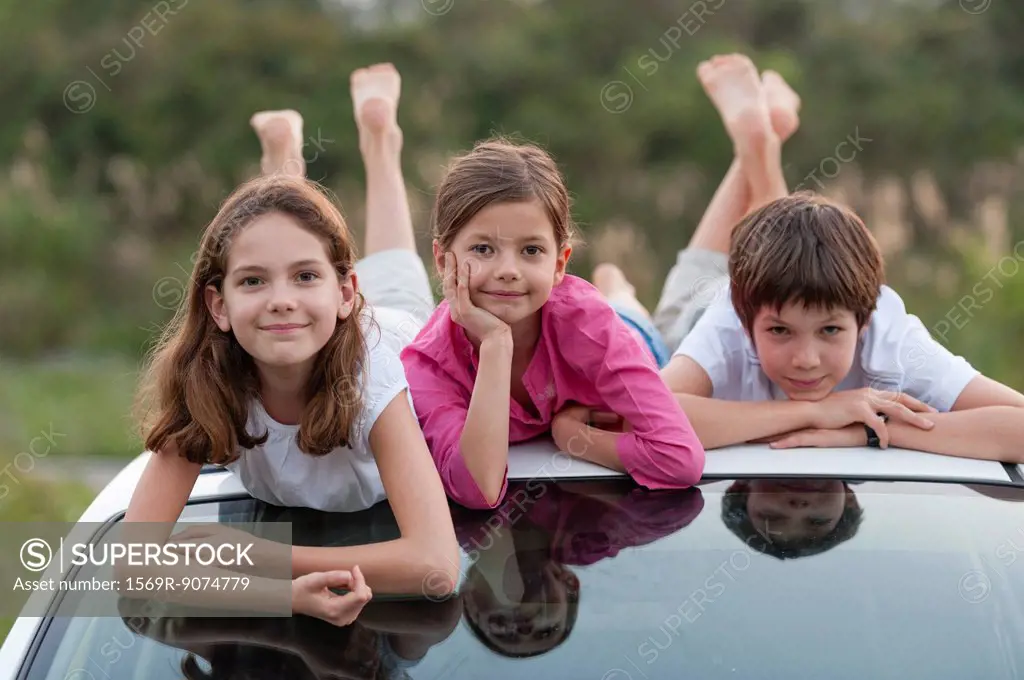 Siblings lying on top of car roof, portrait
