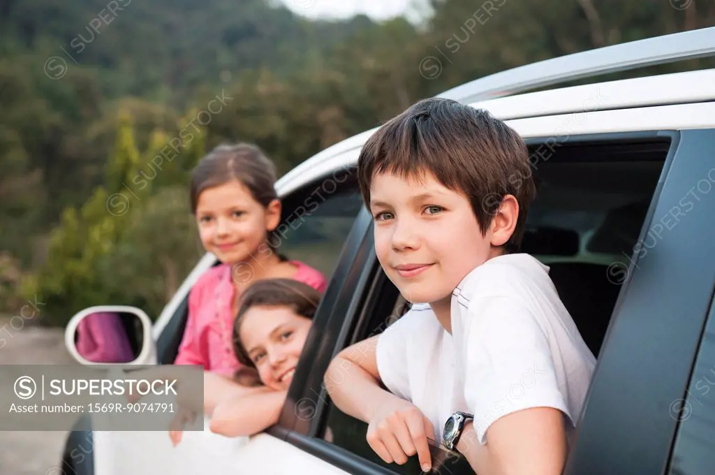 Siblings leaning out of car window, smiling, portrait