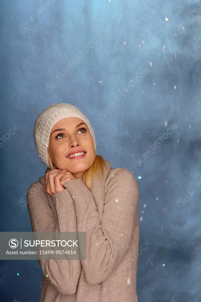 Woman wearing knit hat in front of snowy background, portrait