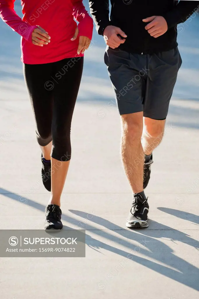 Couple jogging side by side, low section
