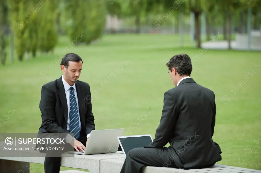 Businessmen using laptop computers outdoors