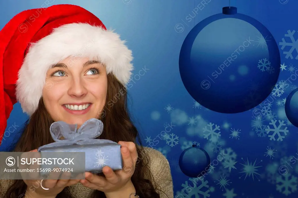 Young woman in Santa hat holding Christmas gift, portrait