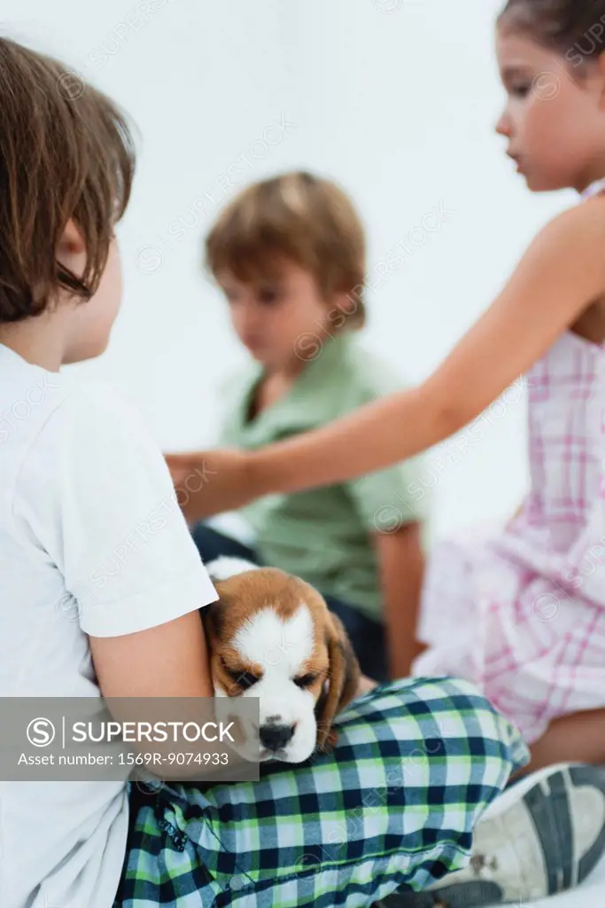 Children hanging out, boy in foreground holding beagle puppy