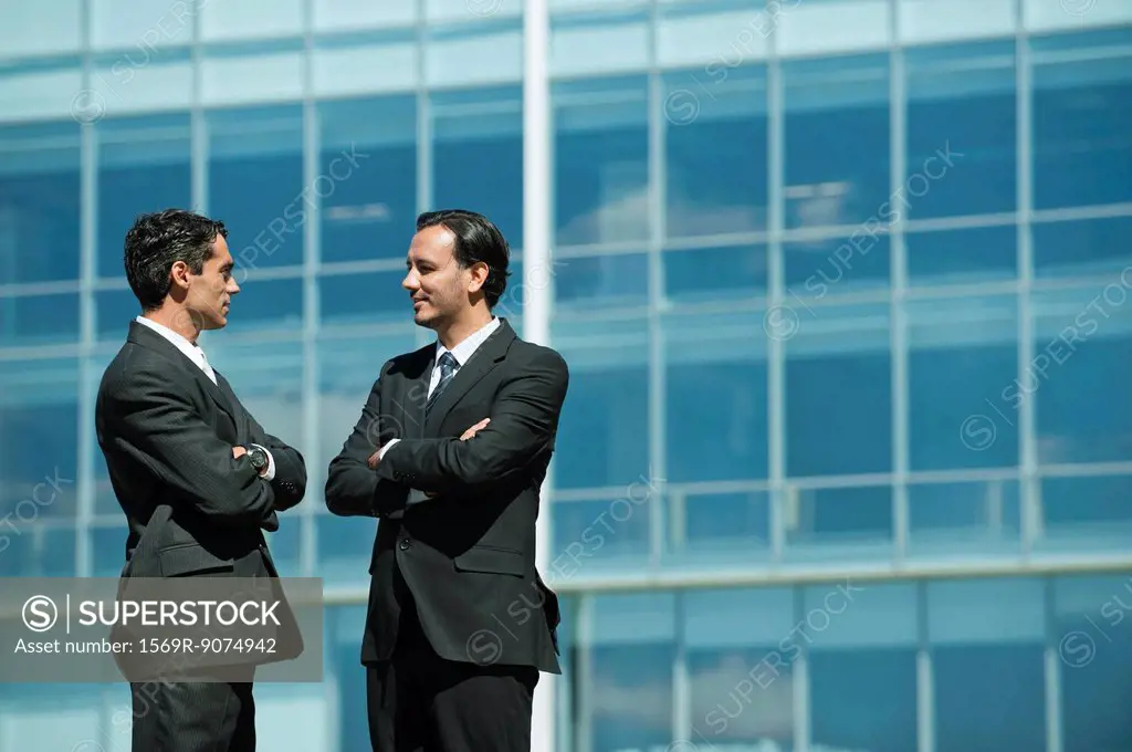 Business executives standing in front of office building talking