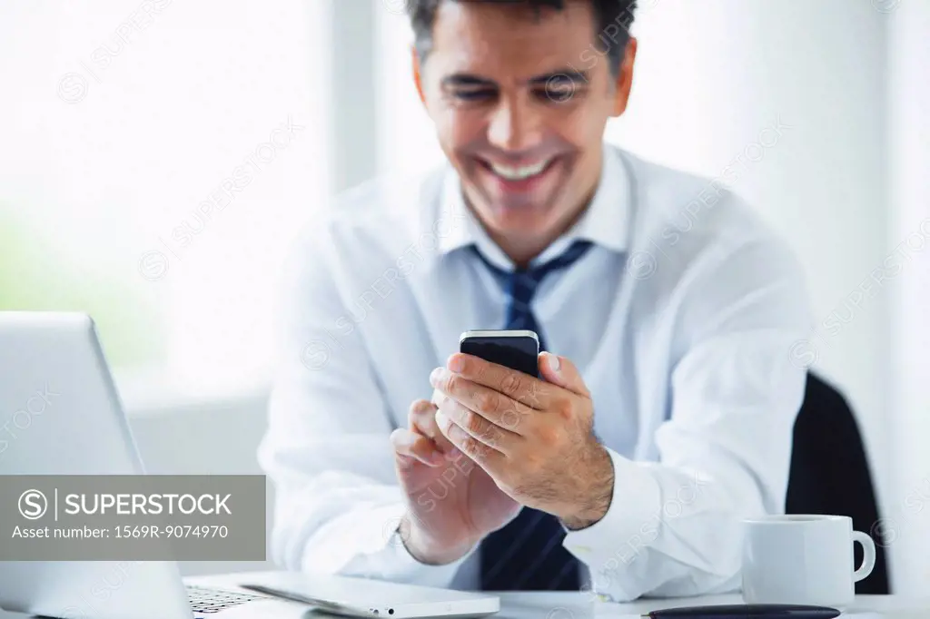 Businessman using smartphone, smiling