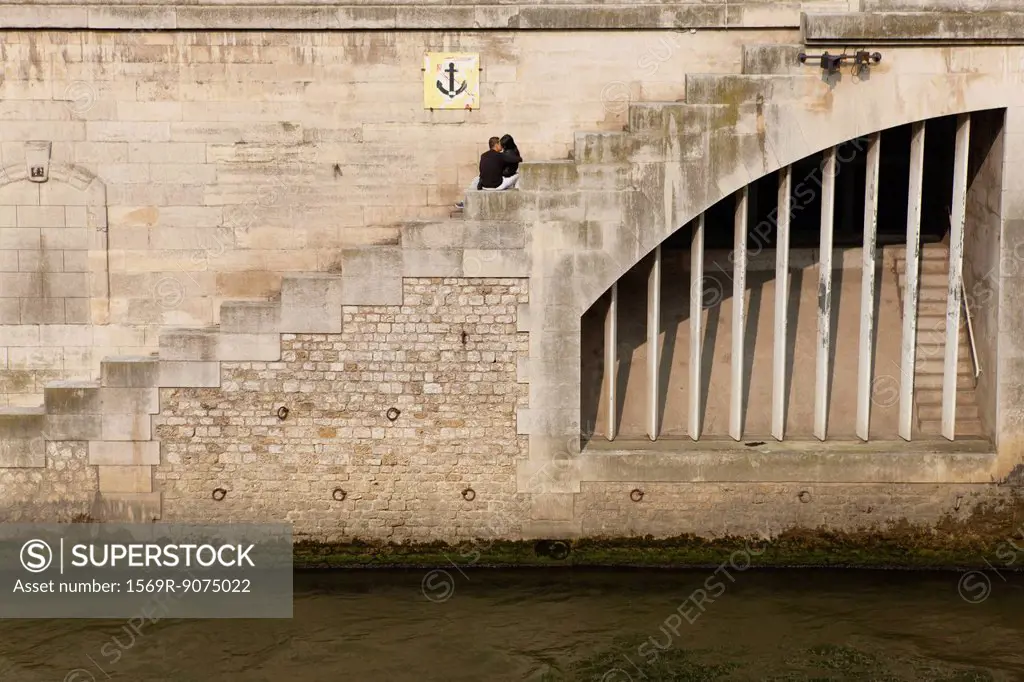 Couple embracing on steps by river