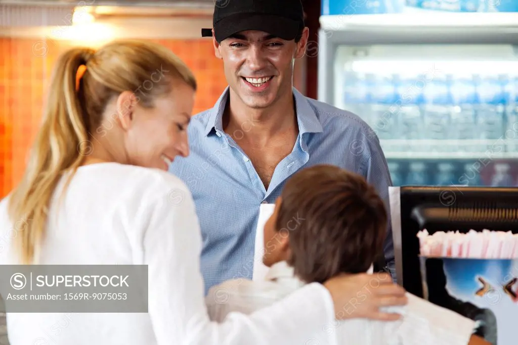 Man serving mother and son at snack counter
