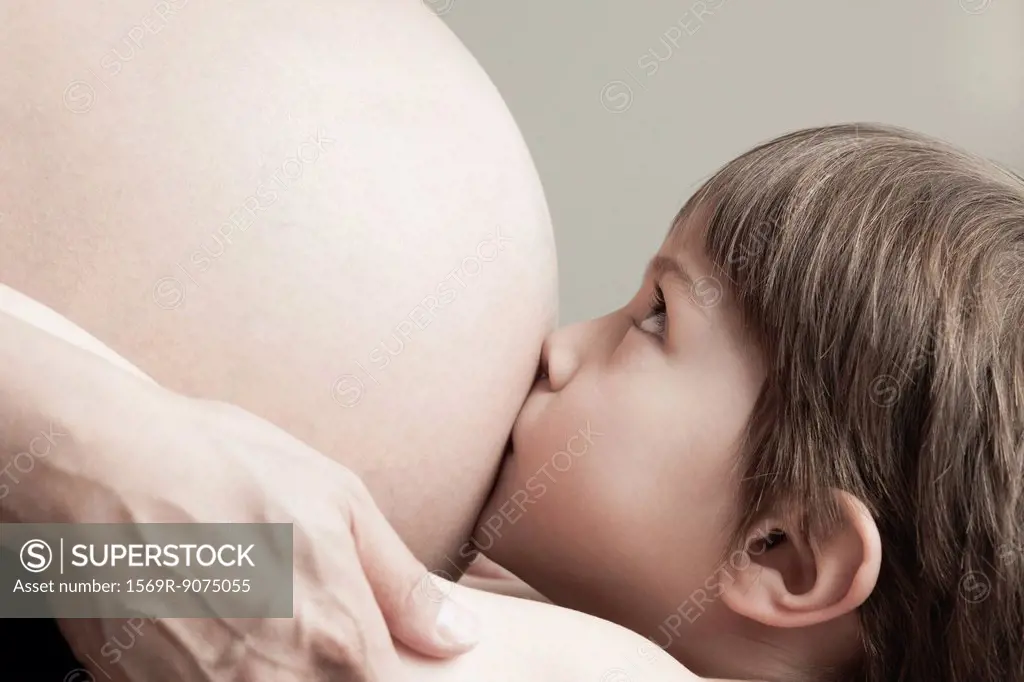 Boy kissing pregnant mother´s stomach, cropped