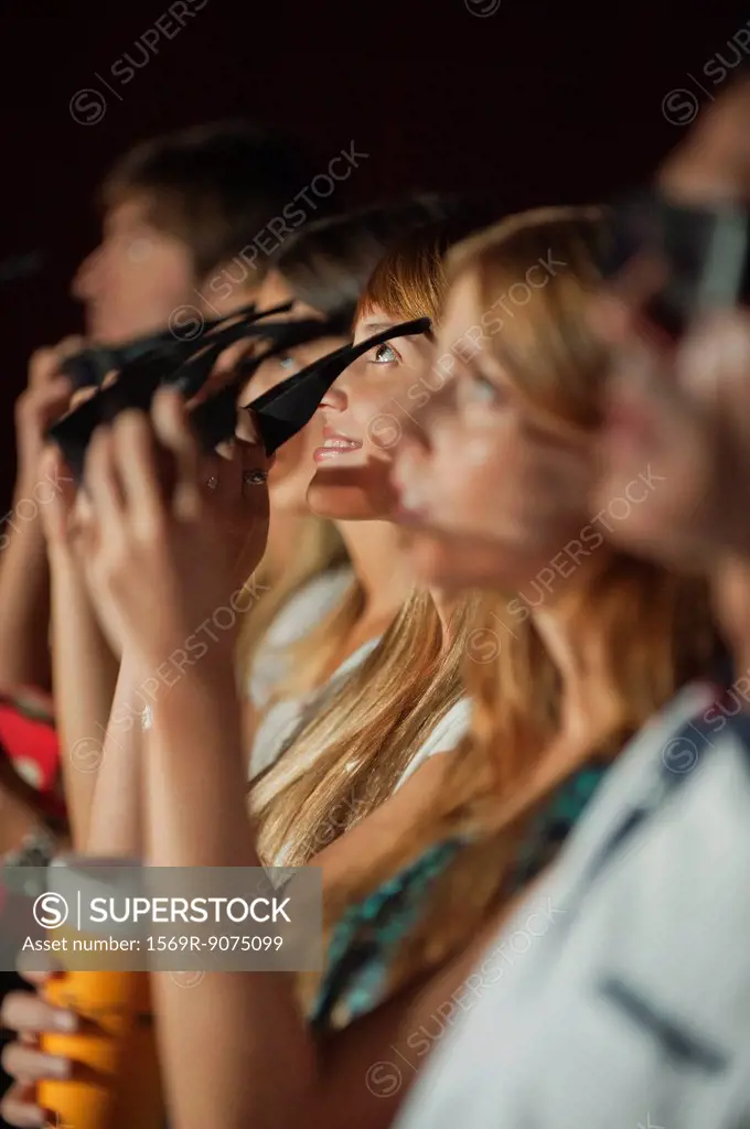 Audience in movie theater putting on 3_D glasses