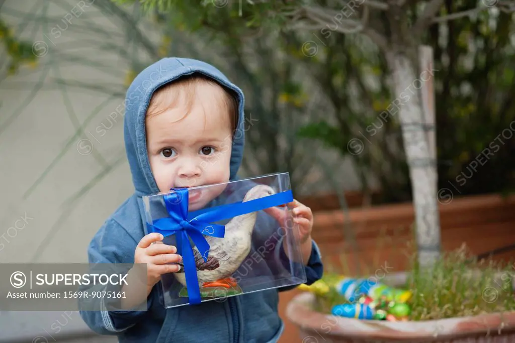 Toddler boy biting box containing Easter candy