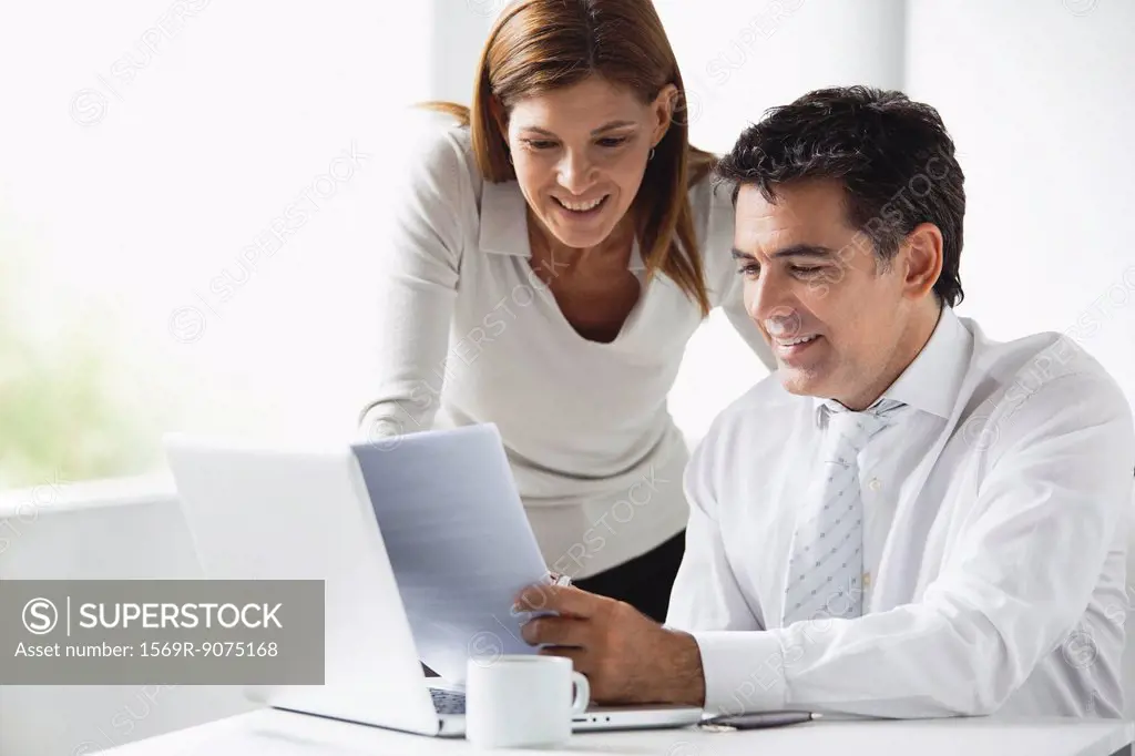 Business colleagues looking at laptop computer together